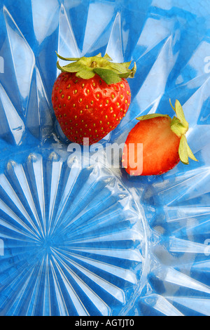 SSK79559 Frucht zwei frische rote Erdbeeren im Schnitt Glasplatte vor blauem Hintergrund Stockfoto