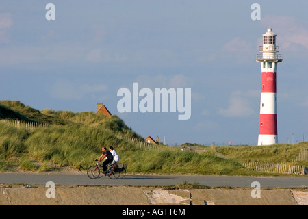 Menschen fahren Fahrräder hinter dem Leuchtturm von Nieuwpoort in Nieuwpoort in der Provinz Westflandern-Belgien Stockfoto