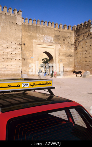 Petit Taxi parkt in der Nähe des Bab Ain Zliten Tors, Fes Medina, Marokko, mit befestigten Mauern und historischer Architektur im Hintergrund. Stockfoto