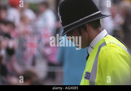 Polizist blickte auf den Boden in Leuchtweste und traditionellen Polizeihelm Kommunikation anhören Stockfoto