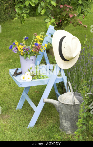 Traditionelle englische Sommer Garten Countryszene mit Schnittblumen im Eimer auf Gartenbank Stockfoto