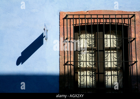 Schmiedearbeiten bedeckt Fenster auf blauen Wand außerhalb eines Gebäudes Stockfoto