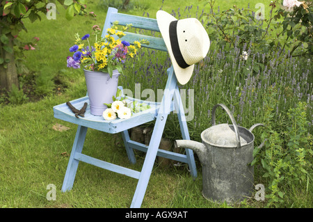 Traditionelle englische Sommer Garten Countryszene mit Schnittblumen im Eimer auf Gartenbank Stockfoto