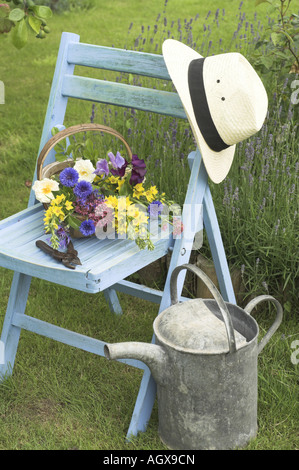 Traditionelle englische Sommergarten-Szene mit Schnittblumen in Trug auf Gartenbank Stockfoto