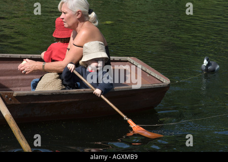 Ein kleines Kind einen Hut hält ein Ruder mit einem Womanin mieten-Boot auf dem Fluss Stour am historischen Flatford in Suffolk England Stockfoto