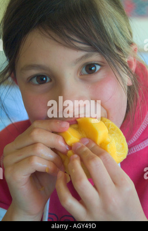 Ein junges Mädchen, das eine süße frische Mango genießt Stockfoto