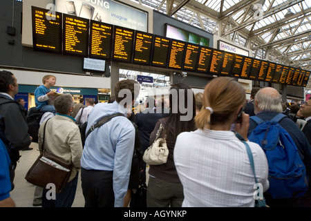 Pendler verzögert im Abfertigungsbereich beobachten Fahrplan an der Waterloo Station-London Stockfoto