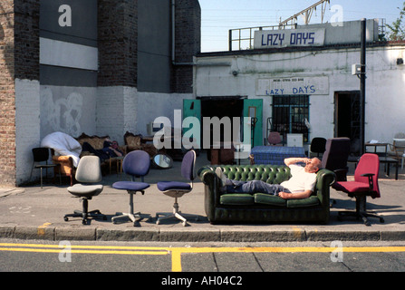 Mann auf einer Couch in einem Second-Hand-Möbel-Shop in Hackey, London, UK Stockfoto