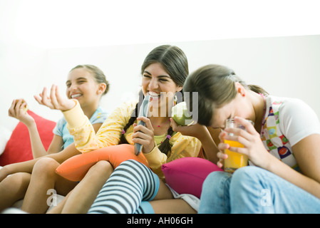 Junge Freundinnen nebeneinander sitzen, lachen Stockfoto