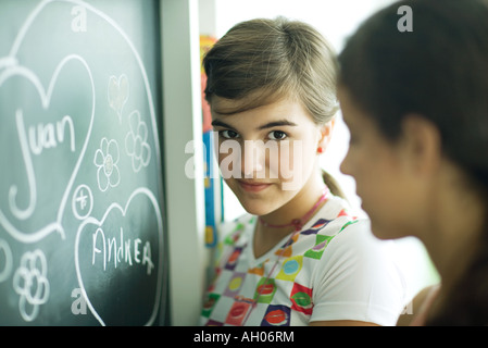 Junge Freundinnen schreiben Namen im Herzen an Tafel Stockfoto