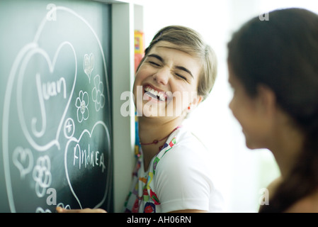 Junge Freundinnen Namen im Herzen an Tafel schreiben, lachen Stockfoto