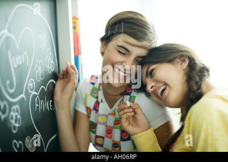 Junge Freundinnen Namen im Herzen an Tafel schreiben, lachen Stockfoto