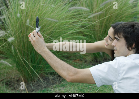 Junges Paar posieren, während Mann Handy hält zu fotografieren Stockfoto