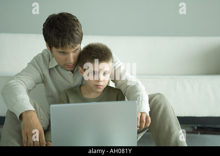 Junge und Laptop zusammen mit Vater Stockfoto