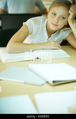 Junge Frau in der Universitätsbibliothek zu studieren, stützte sich auf Buch und wegsehen Stockfoto