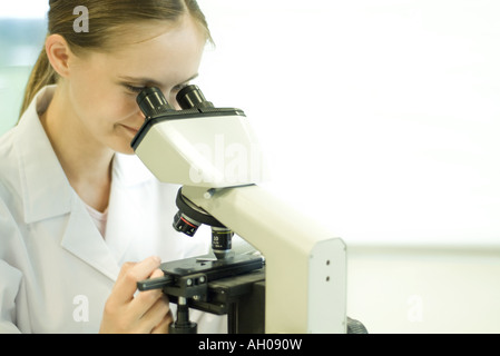 Junge Wissenschaftlerin Durchsicht Mikroskop Stockfoto