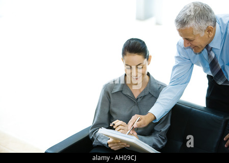 Blick auf Datei zusammen, Mann zeigen, über Frau Schulter schaut den Geschäftspartnern Stockfoto