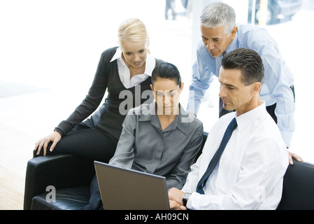 Vier Geschäftspartnern Blick auf Laptop-Computer zusammen Stockfoto