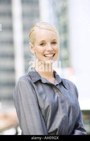 Junge Geschäftsfrau lächelnd in die Kamera, Hüfte aufwärts, Porträt Stockfoto