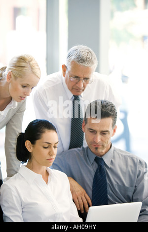 Vier Geschäftspartnern Blick auf Laptop-Computer zusammen Stockfoto