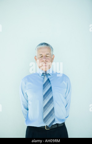 Reife Geschäftsmann stehend, Hände hinter Rücken, Augen geschlossen Stockfoto