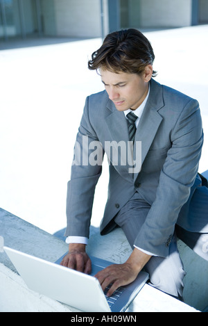 Junger Geschäftsmann, sitzen, Laptopcomputer verwenden, auf der Suche nach unten Stockfoto
