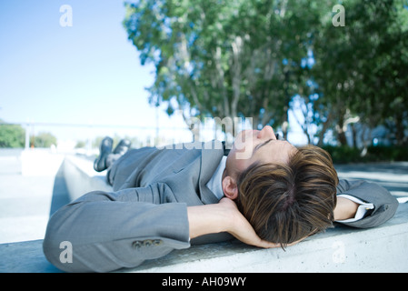 Geschäftsmann am Boden im Freien, liegen die Hände hinter Kopf, volle Länge Stockfoto