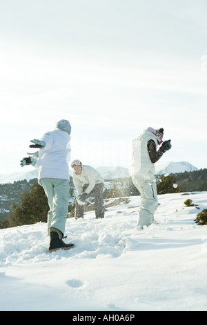 Junge Freunde werfen Schneebälle auf einander, in voller Länge Stockfoto