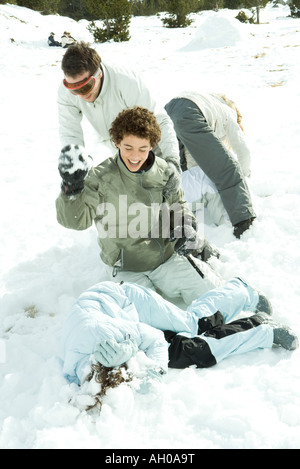 Junge Freunde, die Schneeball kämpfen, einer liegend am Boden, Kopf mit Armen zu bedecken Stockfoto