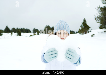 Junge Frau mit Herz aus Schnee, in Schneelandschaft Stockfoto