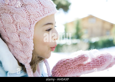 Preteen Mädchen bläst Handvoll Schnee in Fäustlinge, Seitenansicht Stockfoto