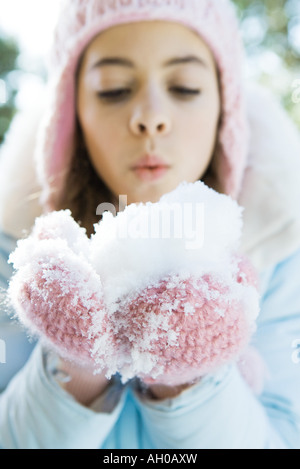 Preteen Mädchen halten Handvoll Schnee in Fäustlinge, weht Stockfoto