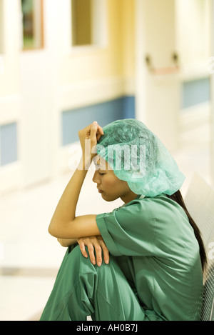 Medizinische Arbeiter sitzen im Krankenhausflur, halten Kopf, Augen geschlossen Stockfoto