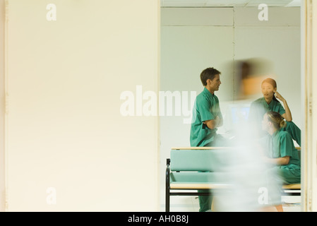 Angehörigen des medizinischen Personals im Chat im Amt, Erwachsene vorbei an Tür, verschwommen Bewegung Stockfoto
