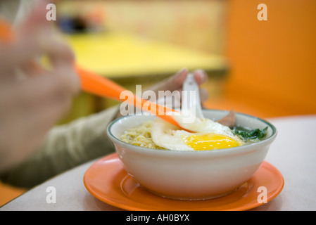 Person Essen Nudelgericht mit Ei, verkürzte Ansicht Stockfoto