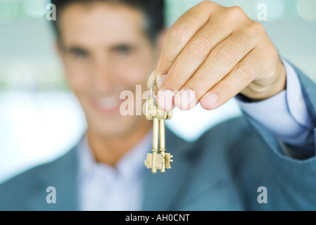 Mann im Anzug hält Schlüssel, Fokus auf Seite halten Schlüssel im Vordergrund Stockfoto