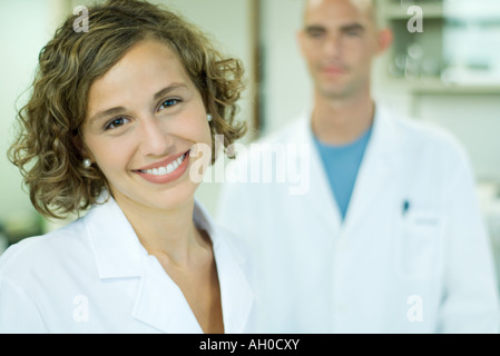 Ärztin lächelnd, männlichen Kollegen im Hintergrund, Porträt Stockfoto