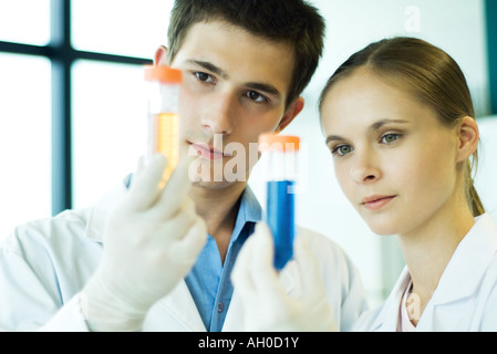 Junge männliche und weibliche Lab Arbeiter, Reagenzgläser hochhalten Stockfoto