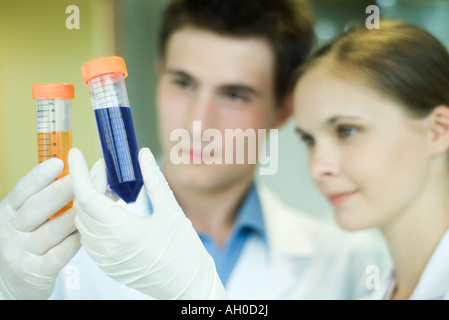 Junge männliche und weibliche Lab Arbeiter, Reagenzgläser hochhalten Stockfoto