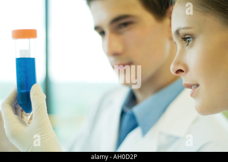 Junge männliche und weibliche Lab Arbeiter, hält Reagenzglas Stockfoto