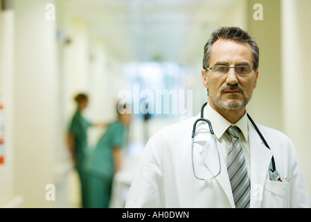 Männlichen Arzt stehen im Krankenhausflur, Blick in die Kamera, Kopf und Schultern Stockfoto