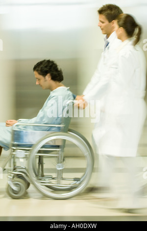 Medizinisches Personal schieben Mann im Rollstuhl, Bewegungsunschärfe Stockfoto