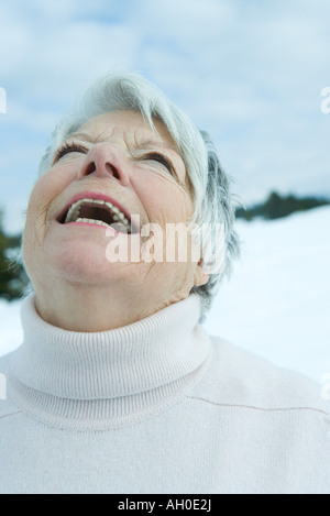 Ältere Frau lachend mit Kopf zurück in verschneiter Landschaft, Porträt Stockfoto