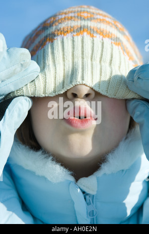 Mädchen ziehen stricken Hut nach unten über Augen, puckering, Nahaufnahme Stockfoto