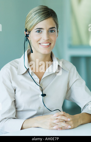 Junge Geschäftsfrau tragen Kopfhörer, lächelnd in die Kamera, Hüfte aufwärts Stockfoto
