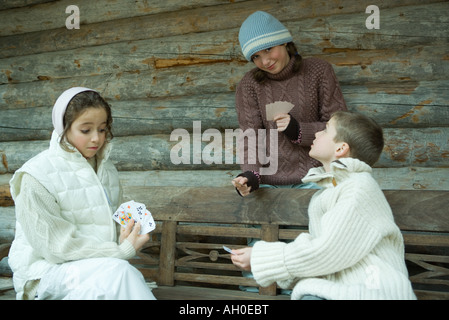 Junge Freunde Spielkarten im Freien, in Winterkleidung gekleidet Stockfoto