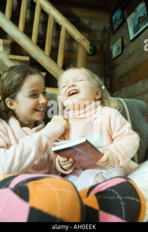 Mädchen und Kleinkind auf Couch sitzen, lachen Stockfoto