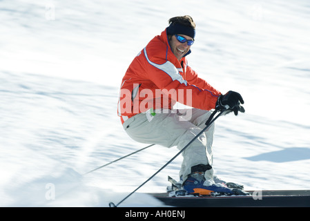 Reifen männlichen Skifahrer auf der Piste, lächelnd in Richtung Kamera, verschwommen Bewegung Stockfoto