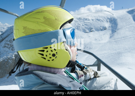 Junge Skifahrer reiten Skilift, Helm, Seitenansicht Stockfoto
