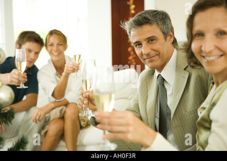 Erwachsene Freunde machen einen Toast mit Champagner, lächelnd in die Kamera Stockfoto